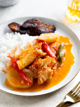 Creamy chicken and vegetable curry with rice and side of barbecue ribs, flavorful and comforting meal.