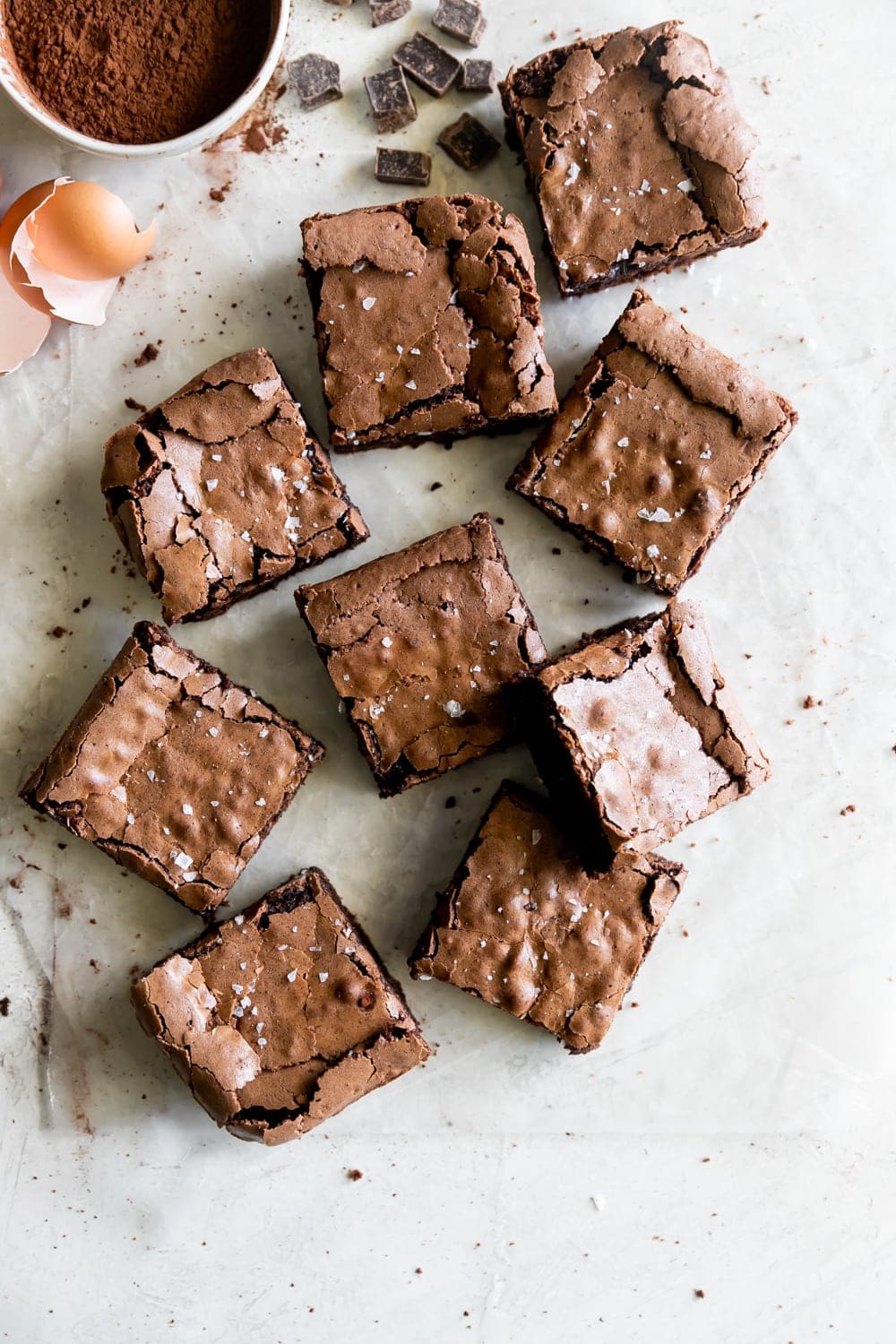 top view of egg shells, cocoa powder, and fudge brownies with flaky salt