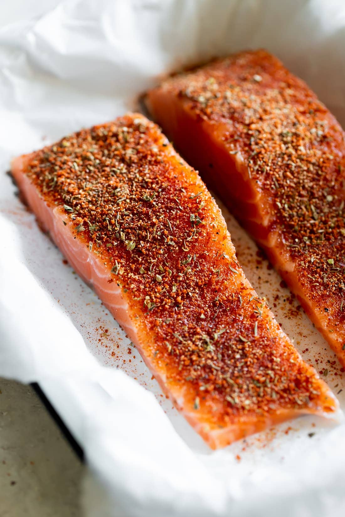 salmon with blackened seasoning on a white baking dish