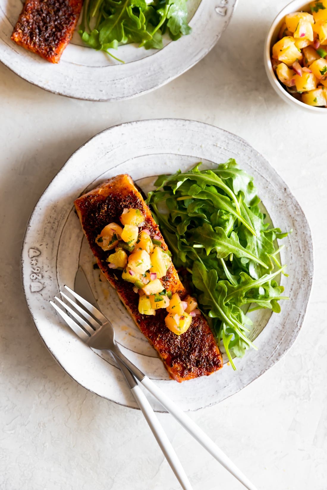 blackened salmon with pineapple jalapeno salsa on a white plate