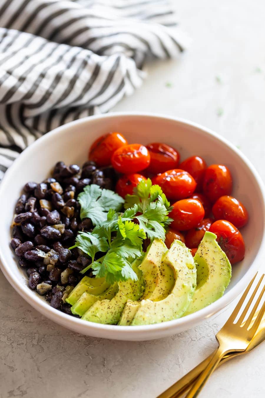 charred tomato salad bowl with sautéed black beans and sliced avocado