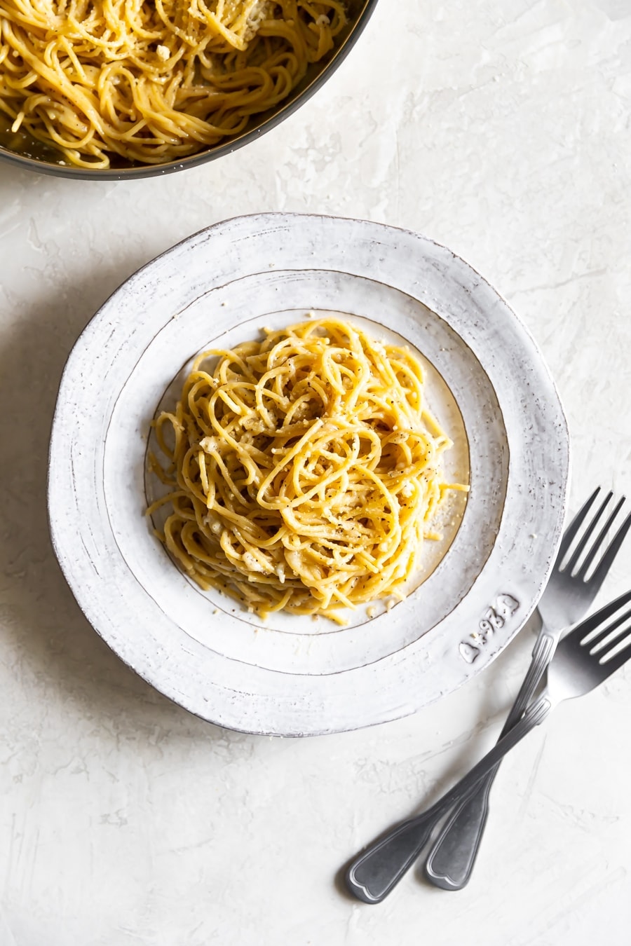 creamy cheese and pepper pasta on a white plate with grated Pecorino on top