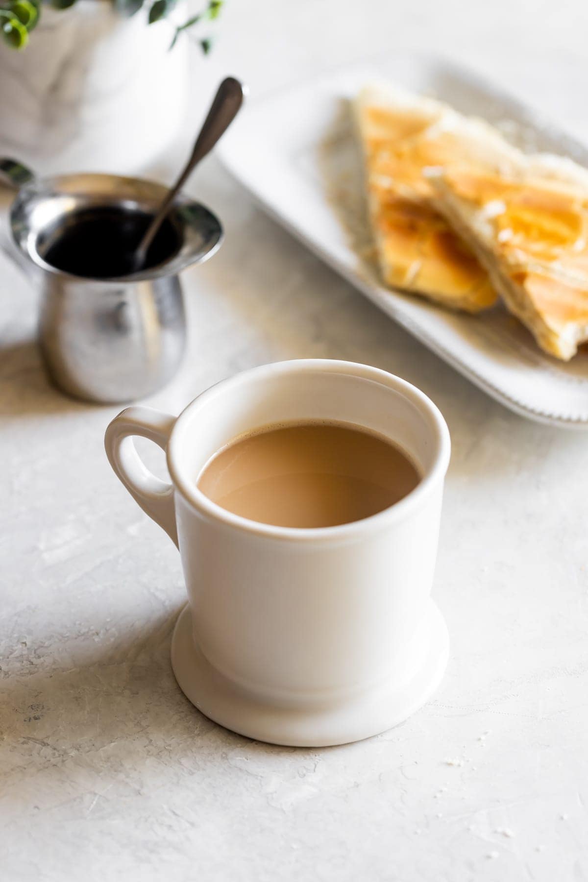 cup of cuban coffee with milk next to espresso cup and cuban toast