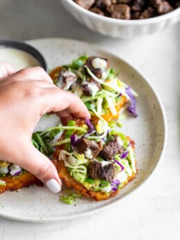 plantains with mashed avocado, salad, carne asada being picked up by hand