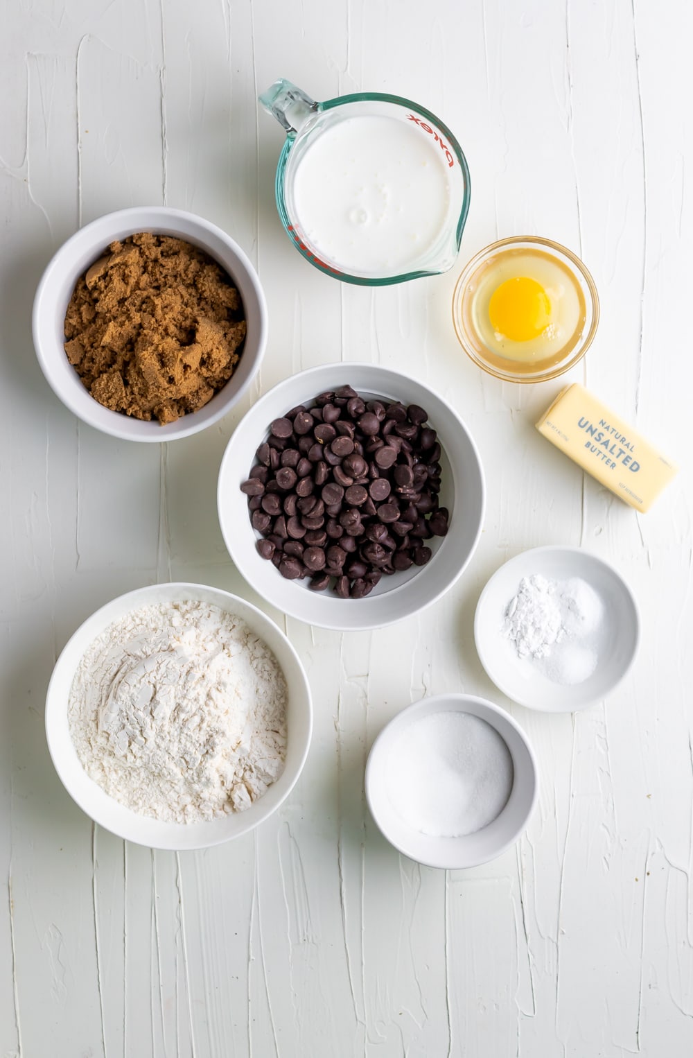 ingredients for chocolate chip muffins in individual bowls on a white table