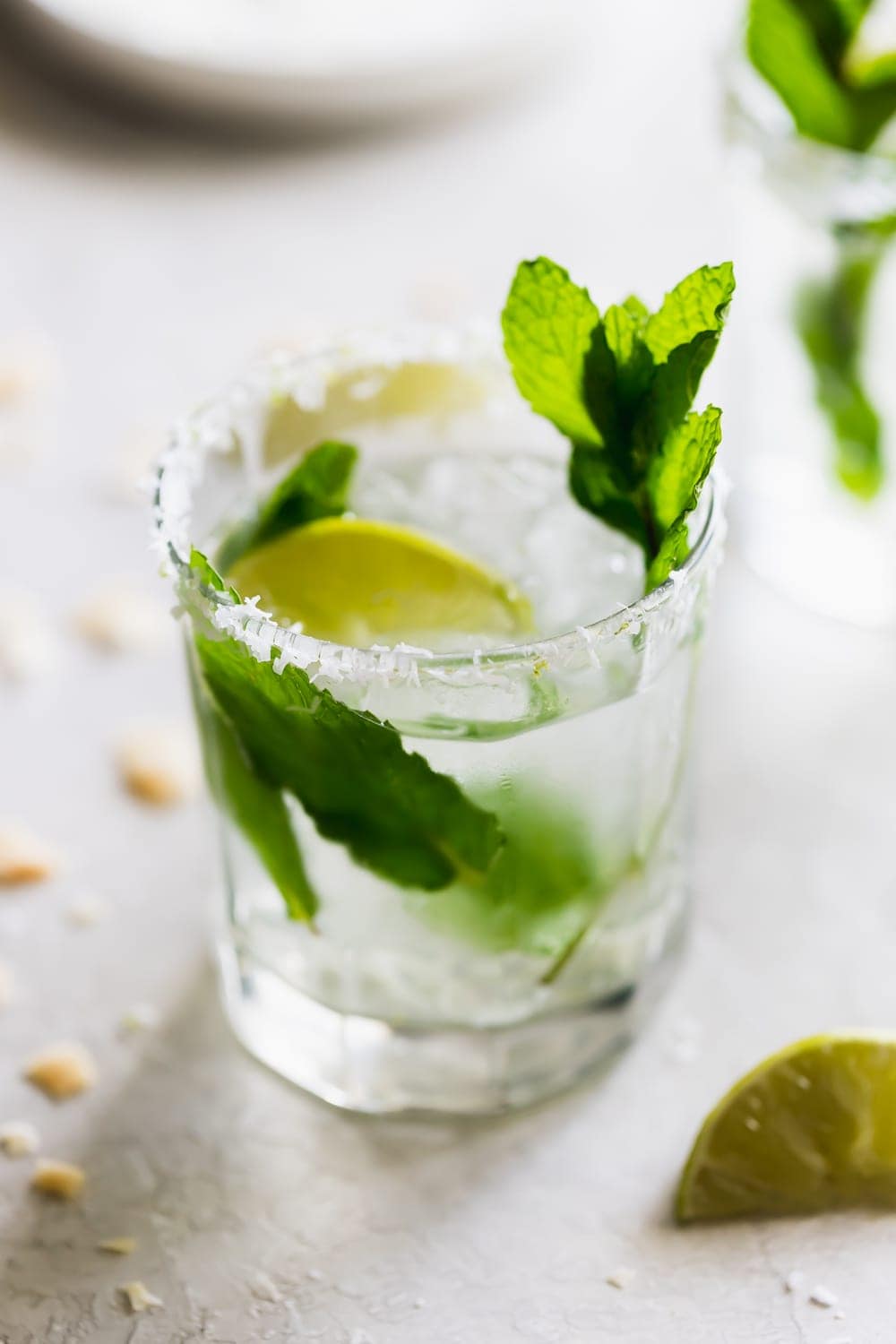 glass of coconut mojito drink with mint leaves and lime wedges