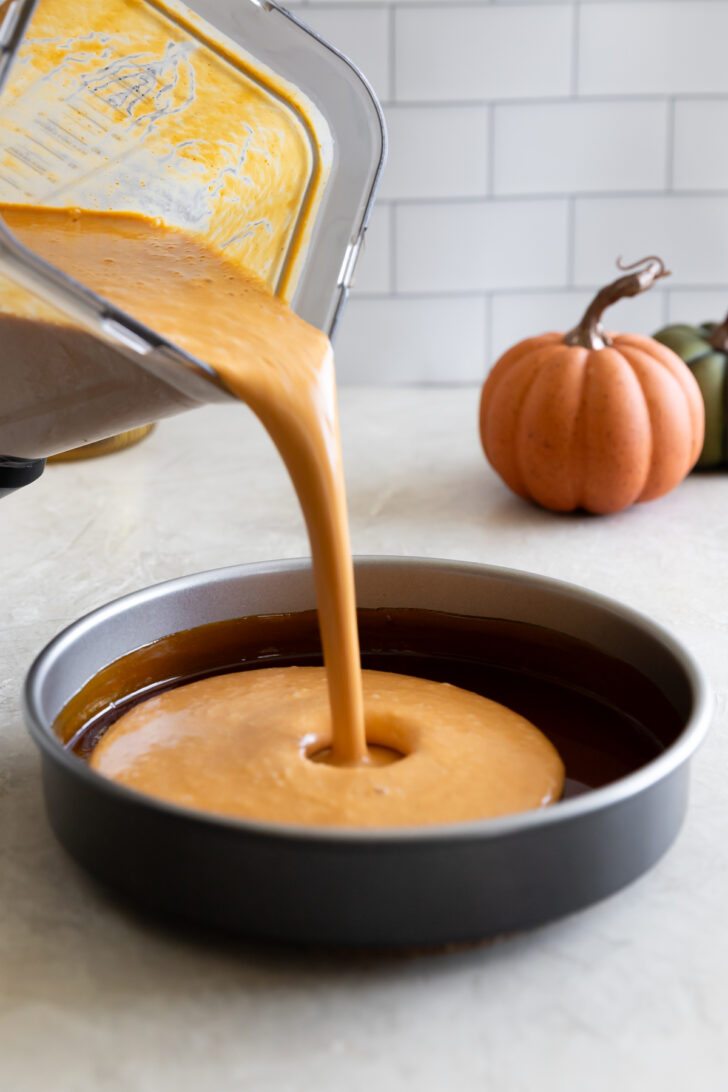 Creamy pumpkin-flavored cheesecake batter being poured into a baking pan, perfect for fall desserts.