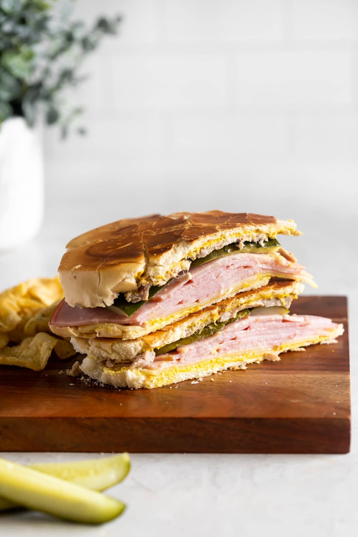 Cuban sandwich sliced in half on a cutting board with chips