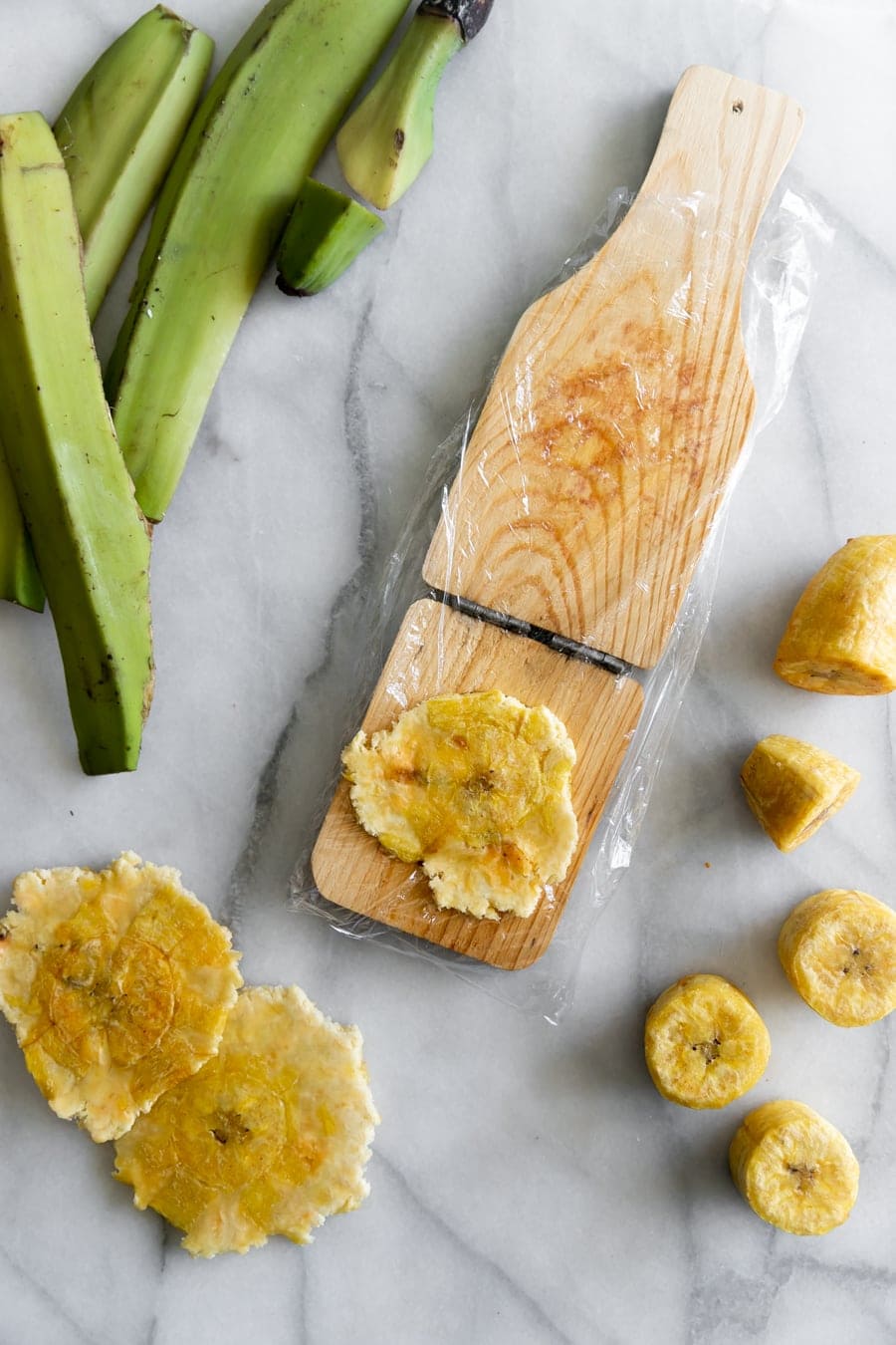 smashing the fried plantains using a tostonera