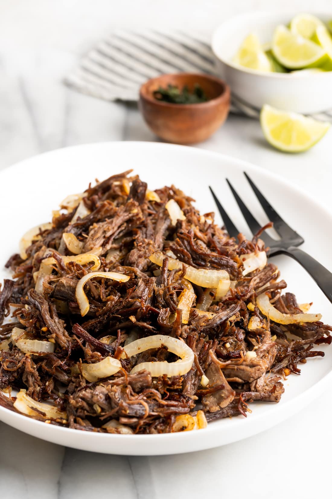 Cuban vaca frita on a white plate with sautéed onions after being pan fried to perfection.