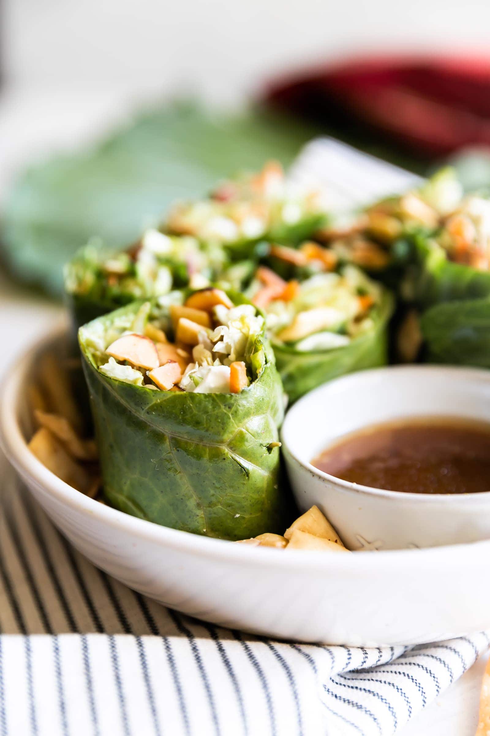 Simple collard green wraps made with avocado, savory green cabbage, carrots, celery, green onions, cilantro, toasted slivered almonds, crisp wontons, and sweet sesame ginger dressing!