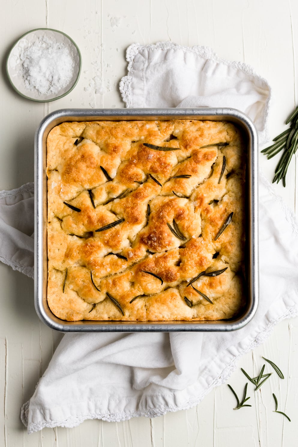 baked focaccia bread with rosemary sea salt in baking dish