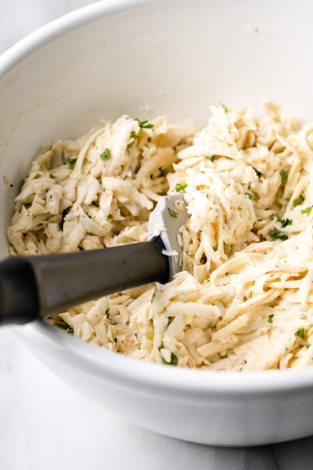 grated malanga mixed with egg, garlic, parsley, salt and pepper in a white bowl