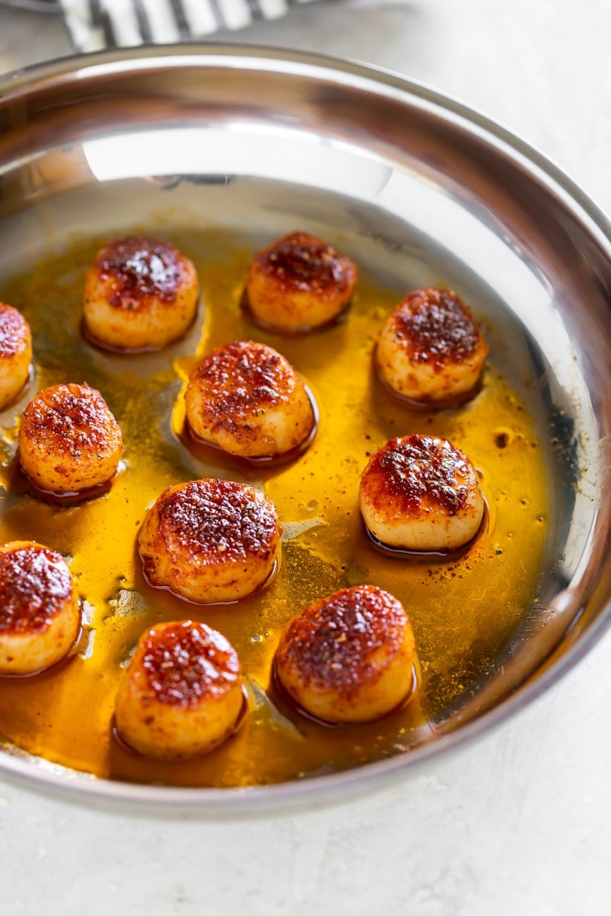 pan seared sea scallops cooked on a pan with olive oil