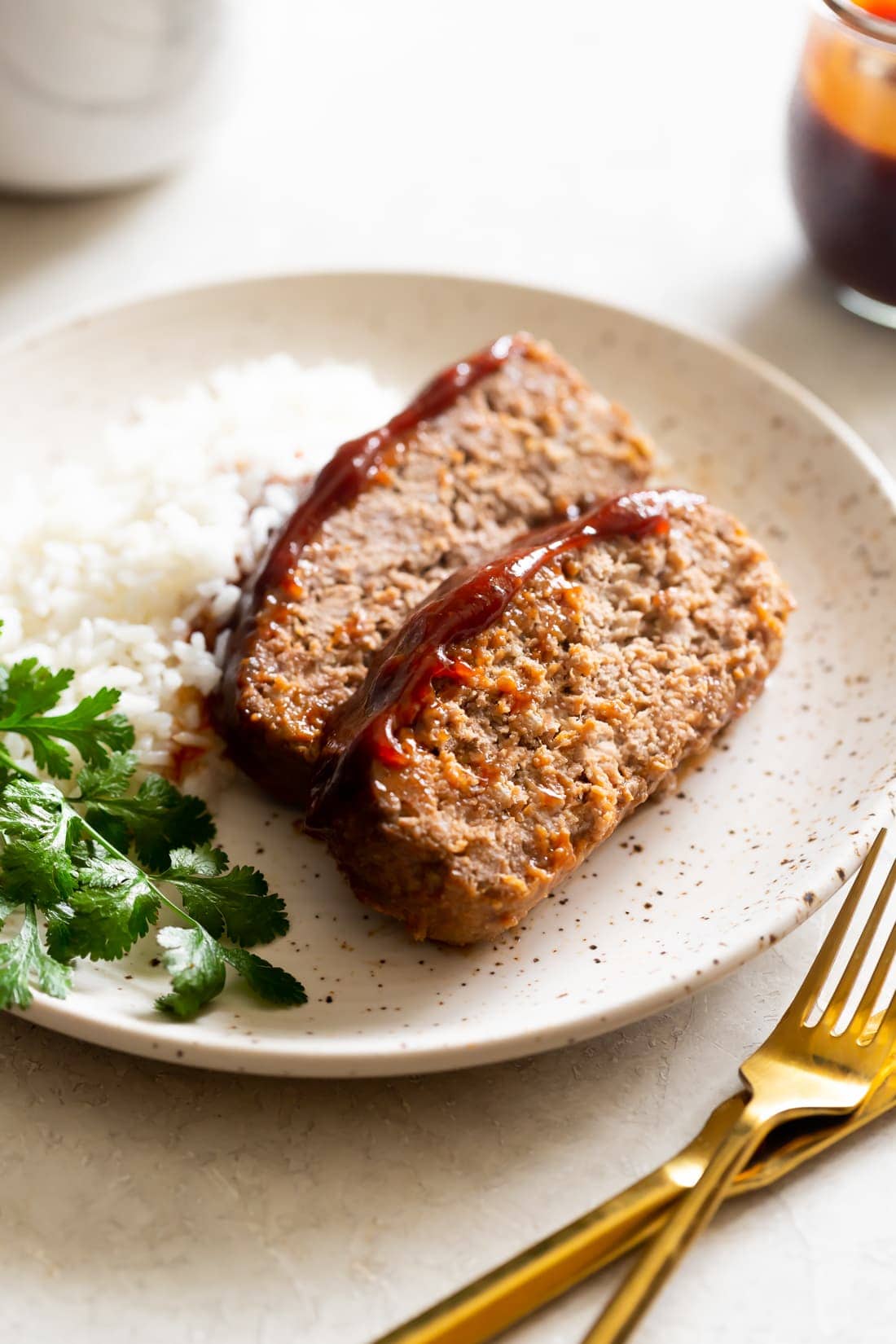 sliced meatloaf with guava bbq sauce served with white rice on a speckled plate