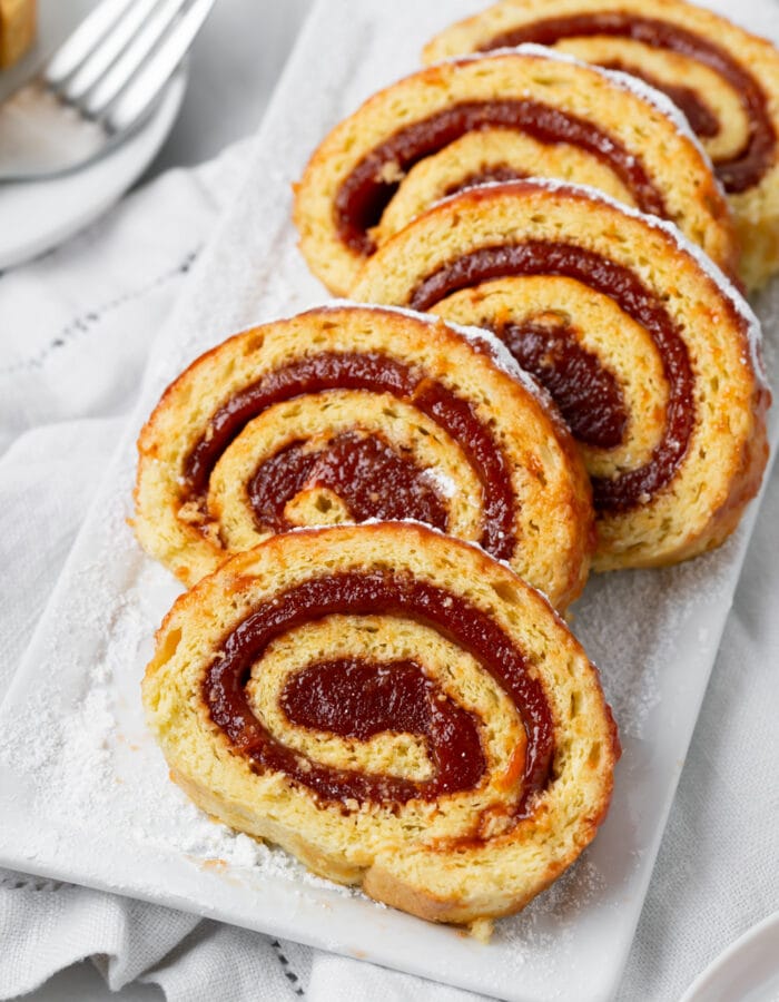 5 pieces of brazo gitano that are laid out on a white platter with a fork on the side