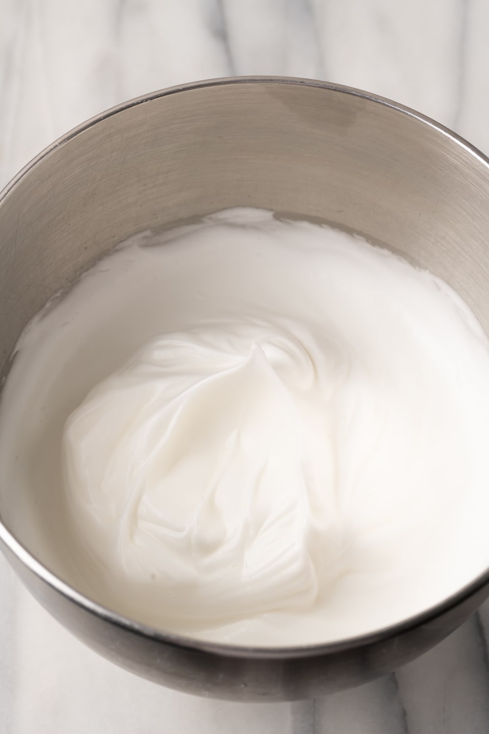 Fresh beat egg whites in a large silver bowl to make a brazo gitano batter