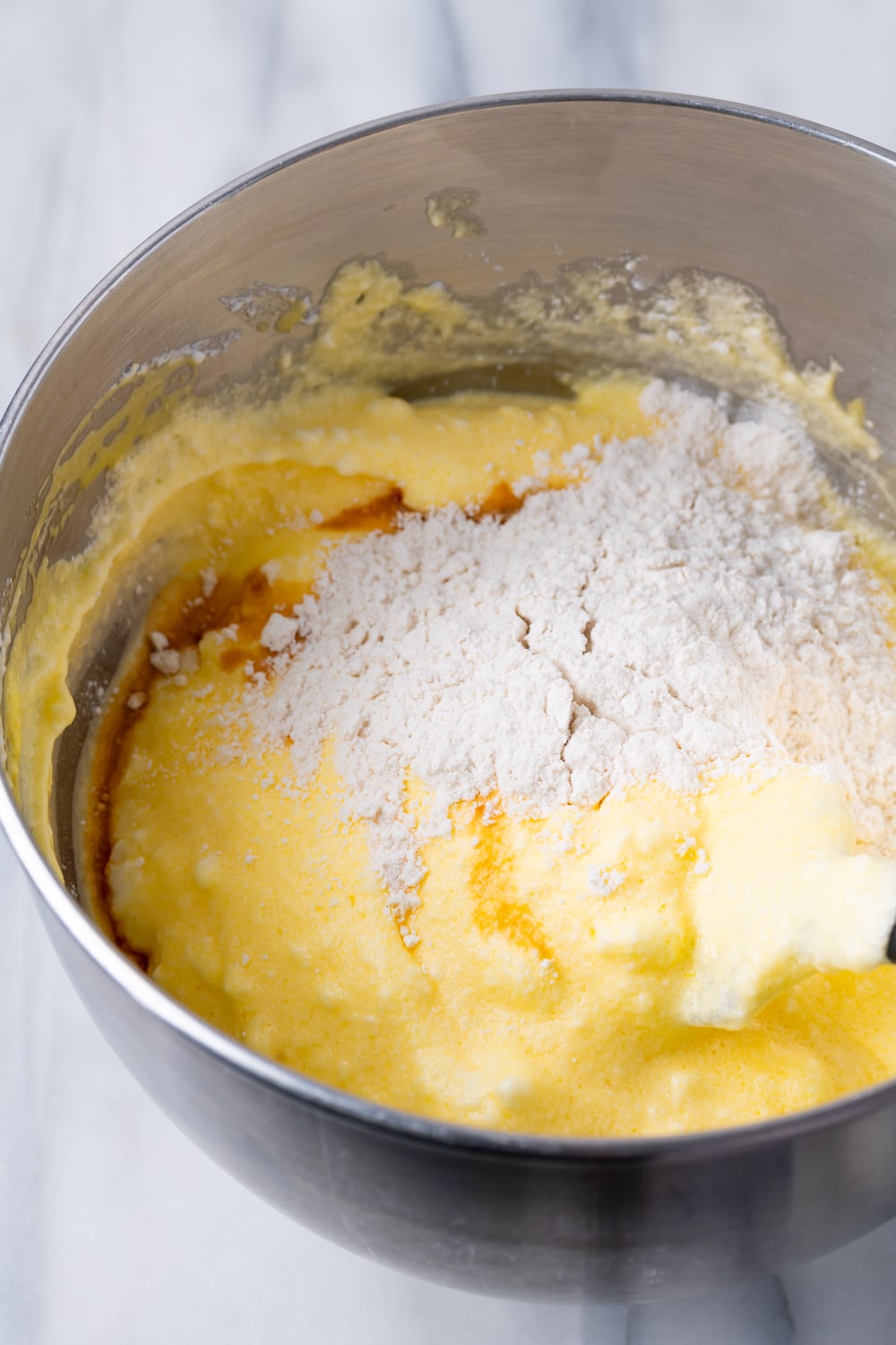 dry ingredients for a guava swiss roll on top of the white ingredients in a large silver bowl before being folded together
