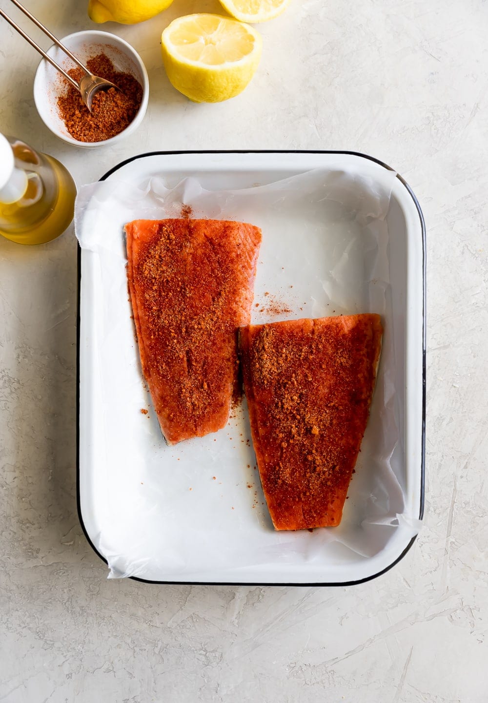 salmon on tray being seasoned with spices
