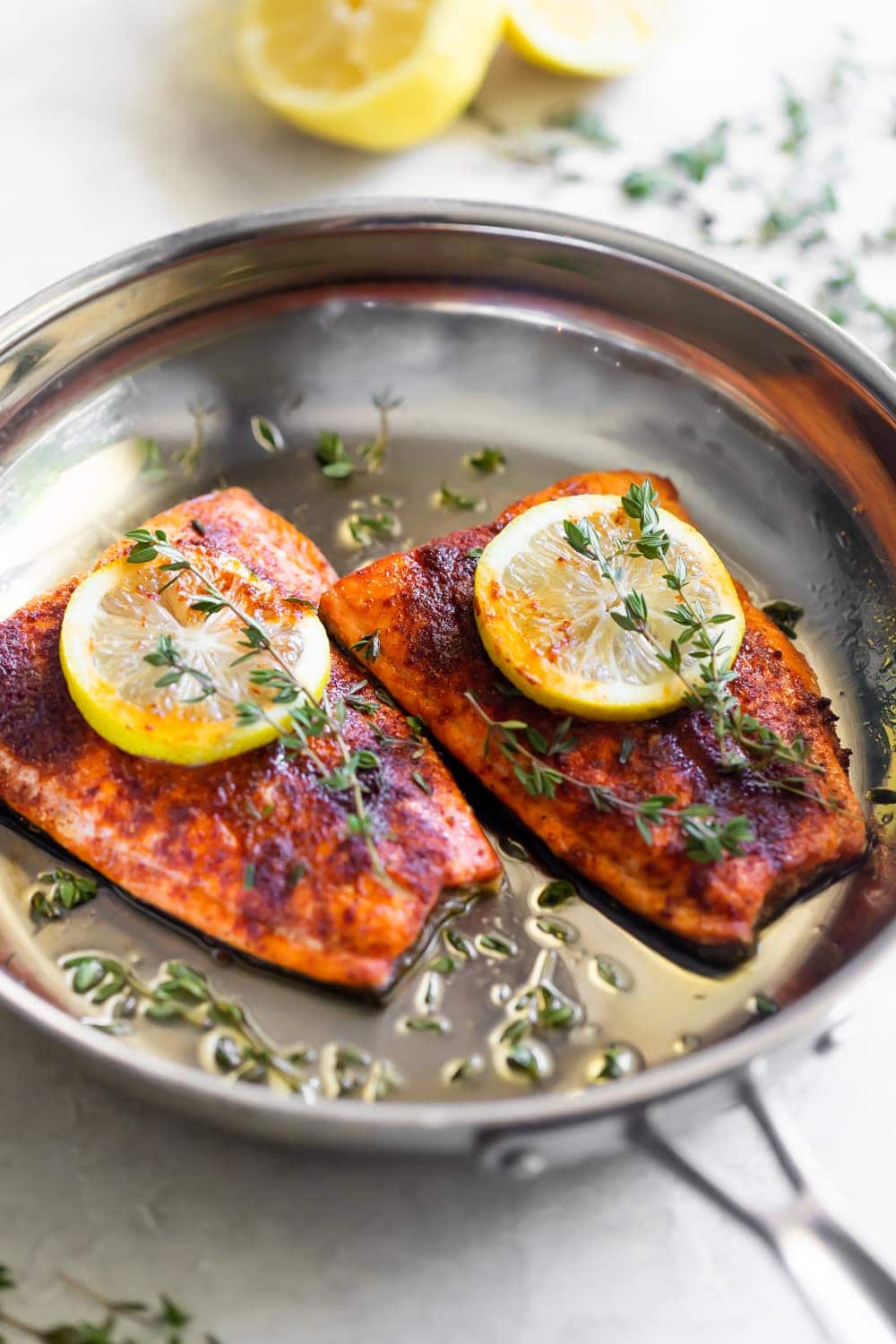 pan seared salmon on skillet with lemon slices