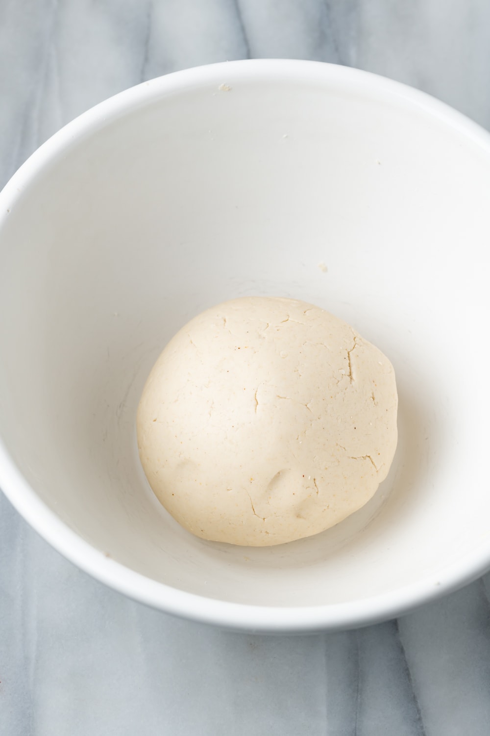 Empanada dough in a smooth ball in a white bowl