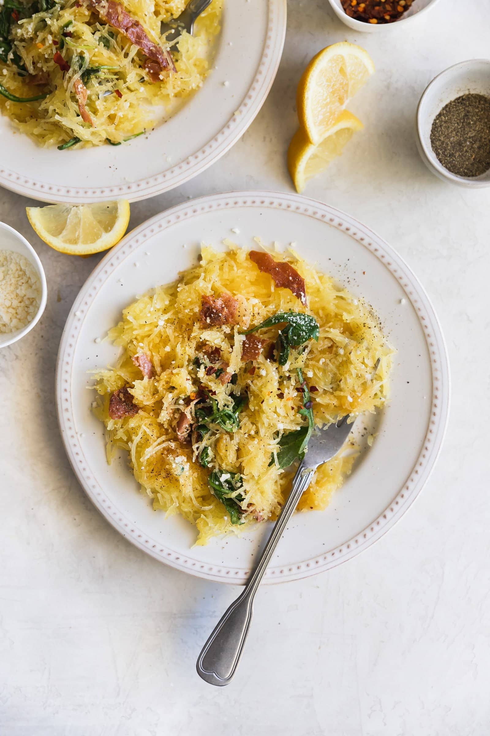 Lemony Cacio e Pepe Spaghetti Squash. A flavorful, low carb meal made with roasted spaghetti squash, lemon, arugula, pancetta, red pepper flakes, grated Parm and fresh pepper. Healthy weeknight dinner!