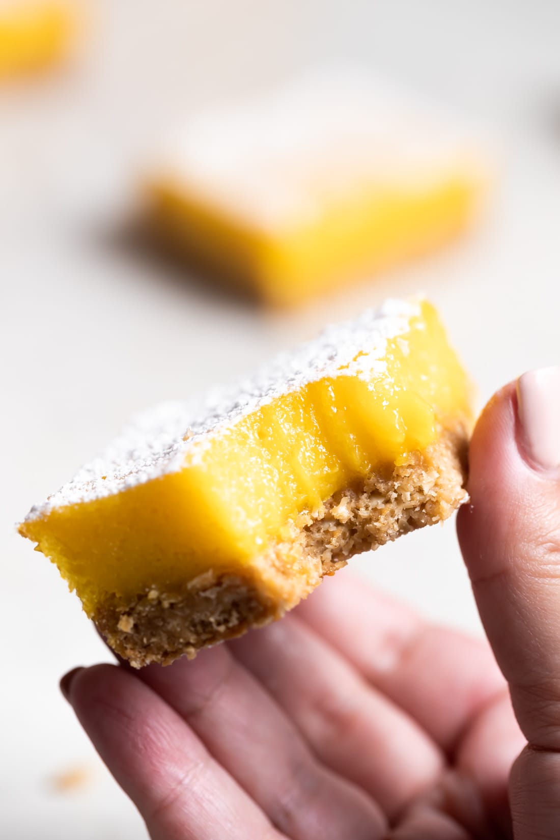 A mango bar with a bite taken out to show the inside being held by a hand