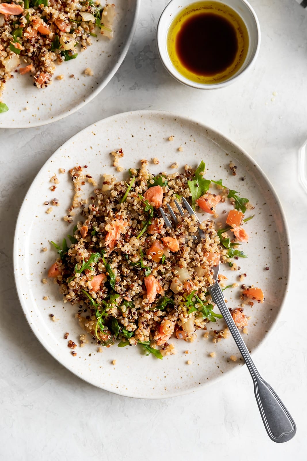 Salmon served with quinoa, tomatoes, onions, and arugula
