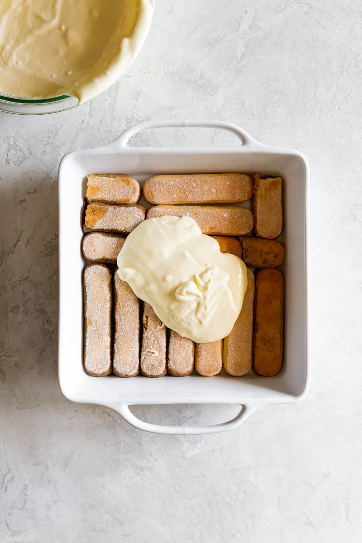 ladyfingers soaked in coffee in a baking dish with mascarpone filling